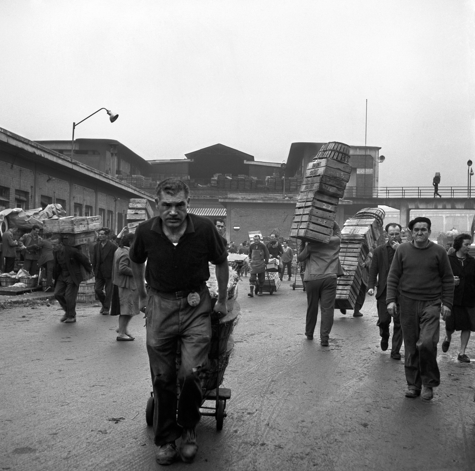 Imagen en blanco y negro de trabajadores del mercado llevando cajas