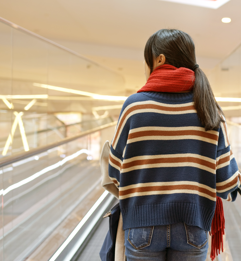 Chica en la cinta mecánica de un centro comercial