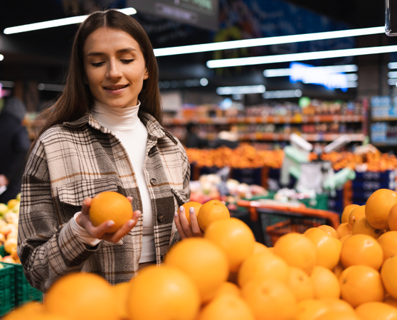 Mujer eligiendo naranjas en un mercado