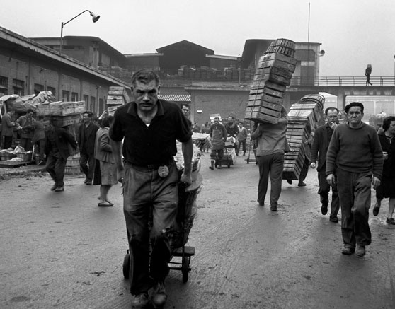 Imagen en blanco y negro de antiguos trabajadores de mercado transportando cajas.