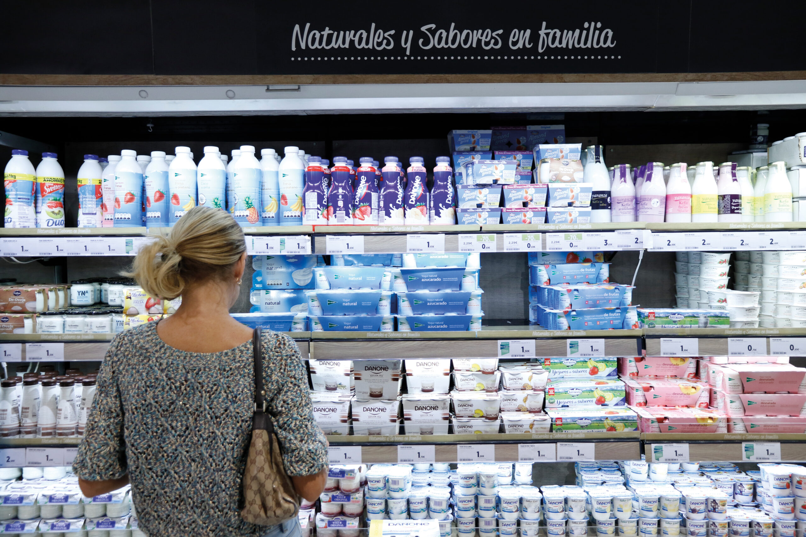 mujer mirando la sección de yogures de un supermercado